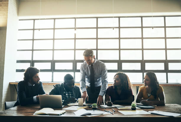 Shot of a well-dressed businessman brainstorming with a team of his colleagues in the office