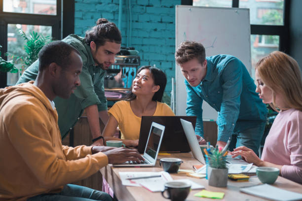 Cheerful business team having job together. They looking at monitor of digital device while locating at table in office. Occupation concept